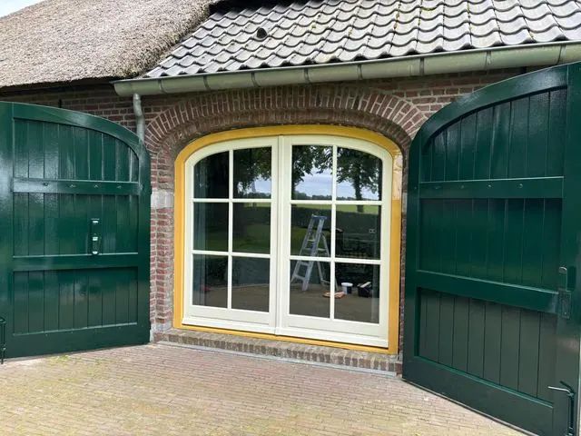 Groen geschilderde stal- of garagedeuren met geel kozijn