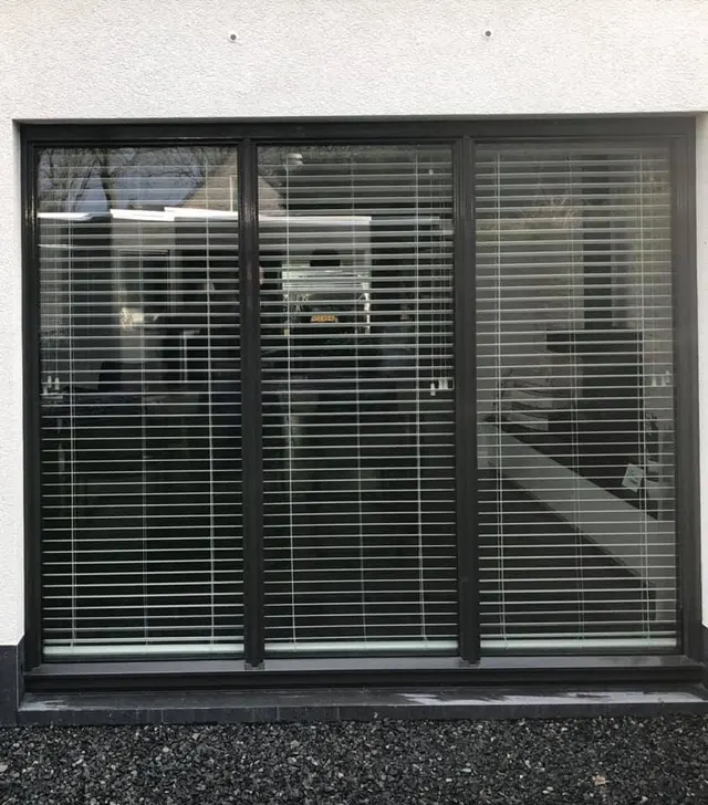Groot zwart raamkozijn met beglazing en jaloezieën