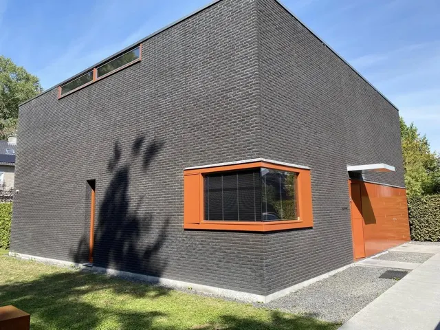 Moderne woning met oranje geschilderde kozijnen en garagedeuren