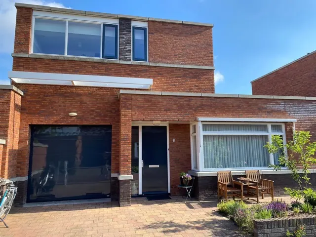 Woning met donkerblauwe garagedeur en geschilderde kozijnen