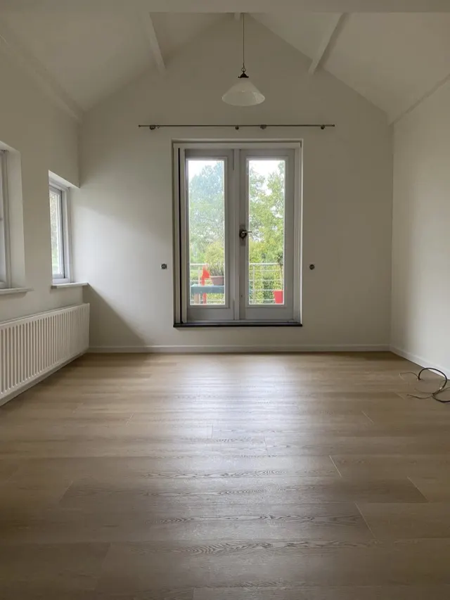 Lichte kamer met getexte wanden en hoog plafond