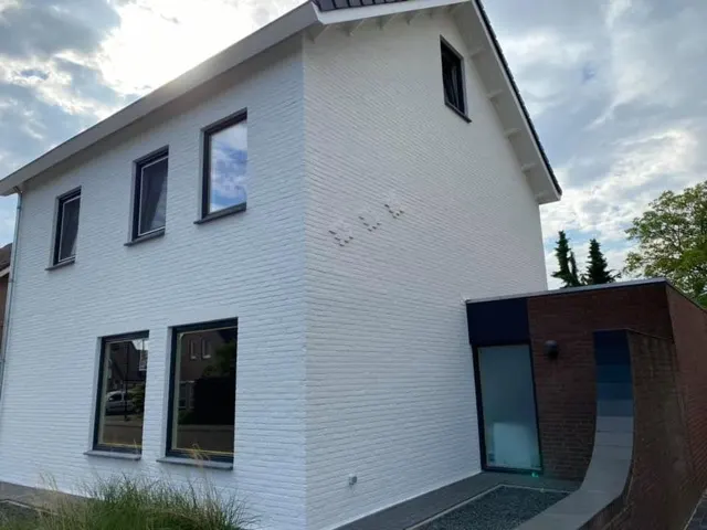 Wit getexte buitengevel met donkere kozijnen
