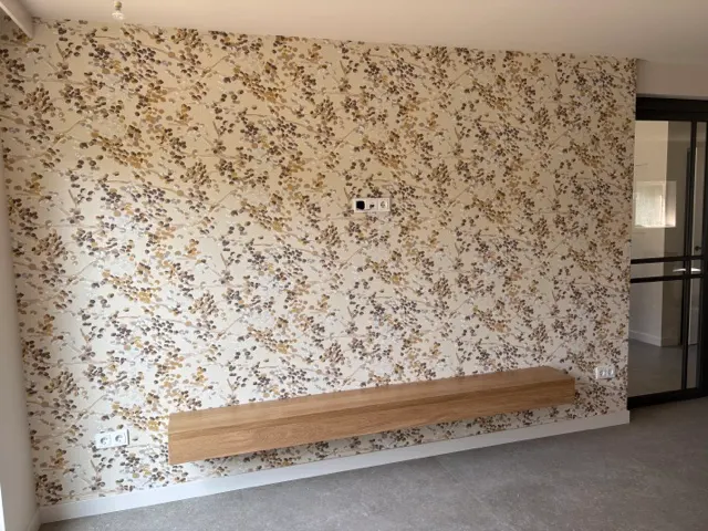 Woonkamer met decoratief bloemenbehang en houten wandbank