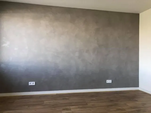 Brede grijze betonlook accentwand in een woonkamer