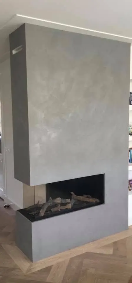 Lichtgrijze betonlook schouw met een moderne hoekhaard