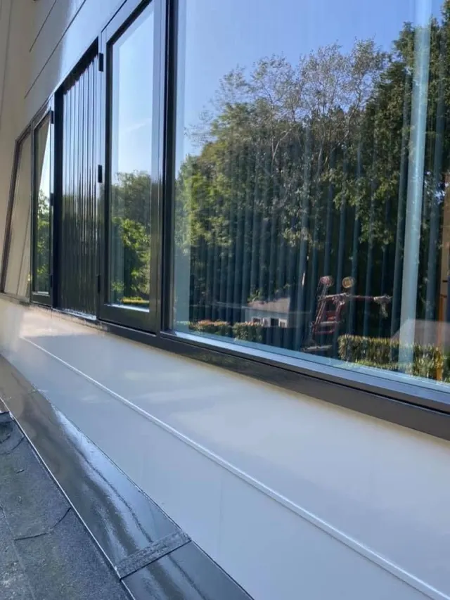 Donkere raamkozijnen met grote glazen ruiten langs een gevel