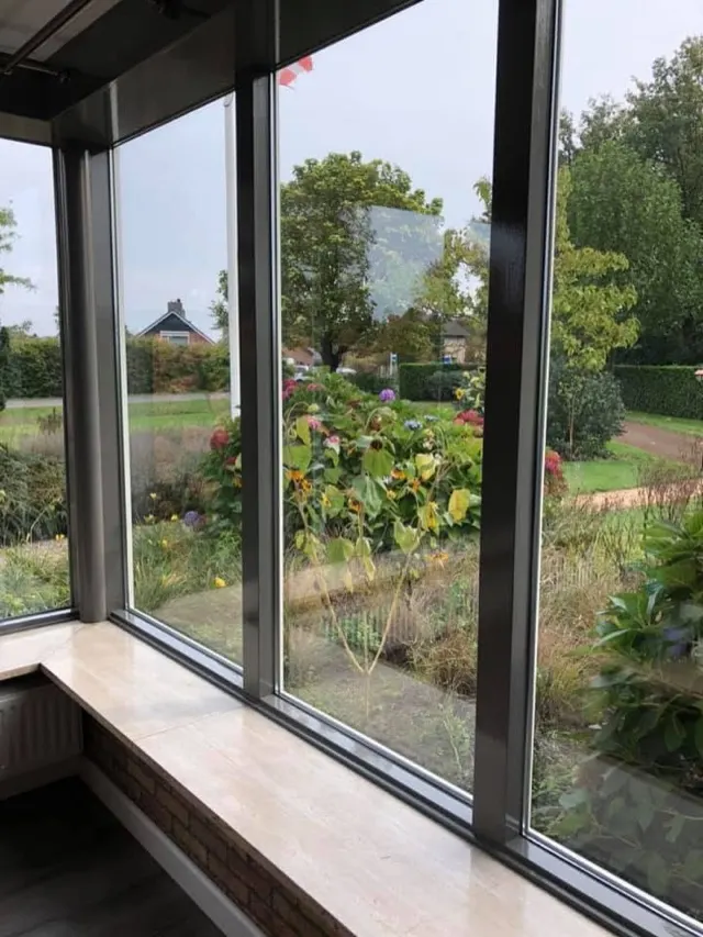 Grote beglaasde raamwand met uitzicht op een tuin