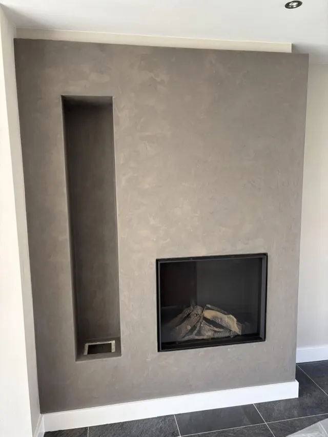 Grijze betonlook schouw met ingebouwde haard